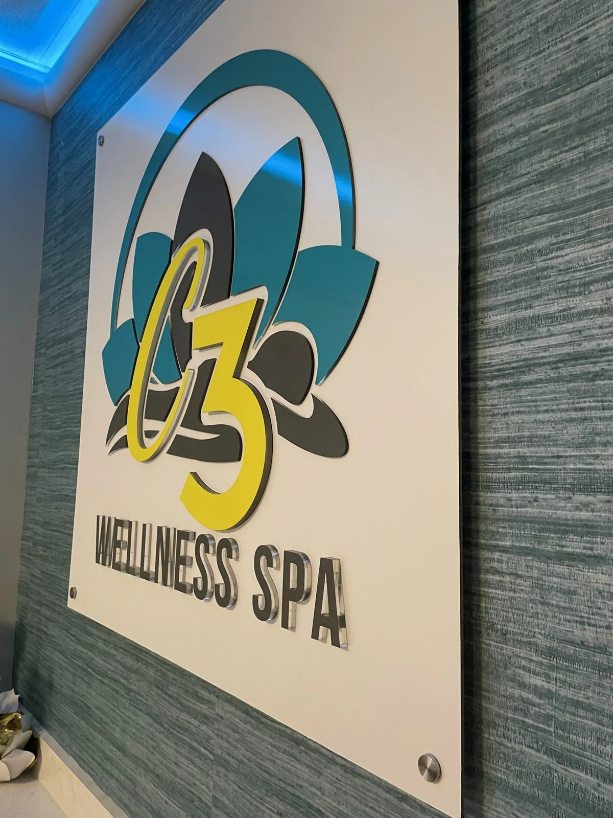 C3 Wellness Spa — C3 Wellness Spa logo panel on a textured lobby wall with blue accent lighting, C3 Wellness project