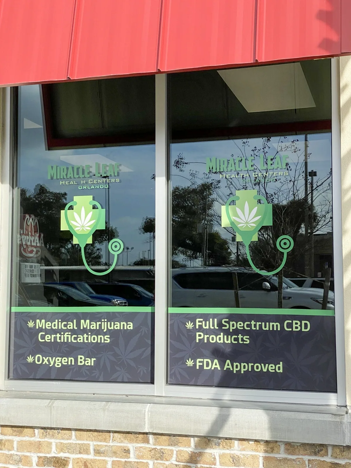 Miracle Leaf Orlando — Storefront window graphics with logo and service list under red awnings, Miracle Leaf Orlando project