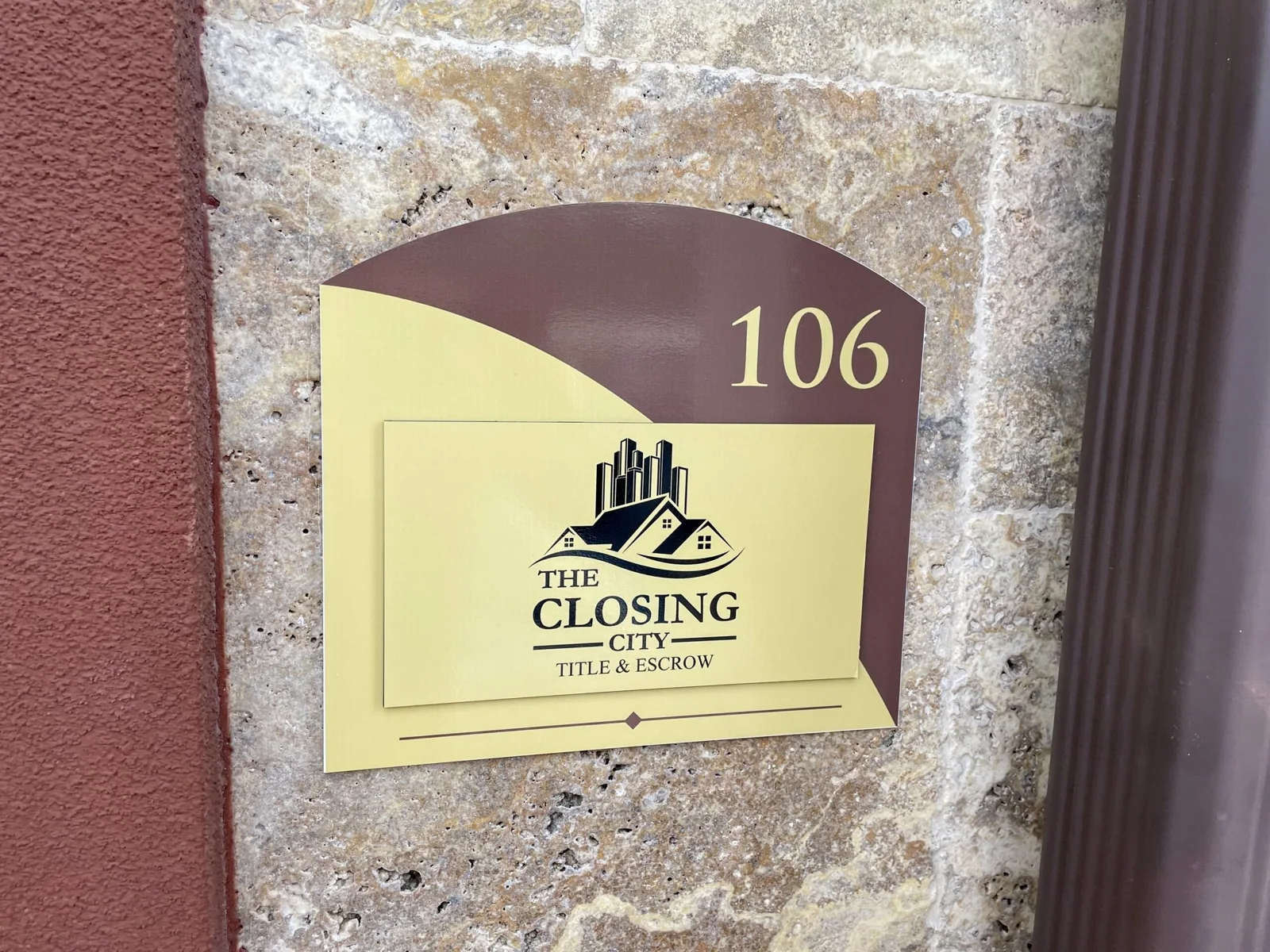 Schenk Enterprises — Suite 106 wall plaque with The Closing City logo on a stone column, Schenk Enterprises project