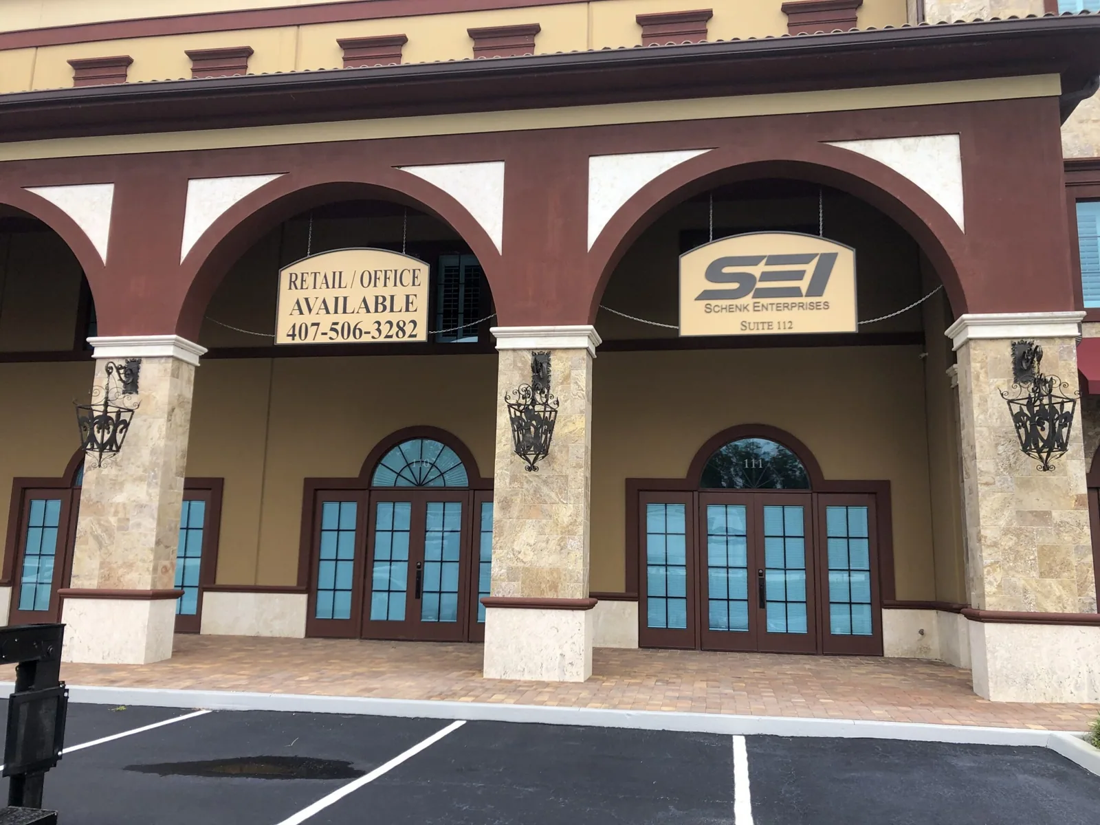 Hanging signs for SEI Schenk Enterprises and retail office space under an arched walkway, Schenk Enterprises project