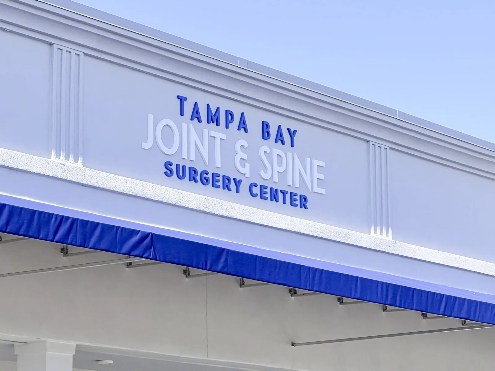 Tampa Bay Joint & Spine — Angled view of Tampa Bay Joint & Spine Surgery Center letters above a blue awning, Tampa Bay Joint project