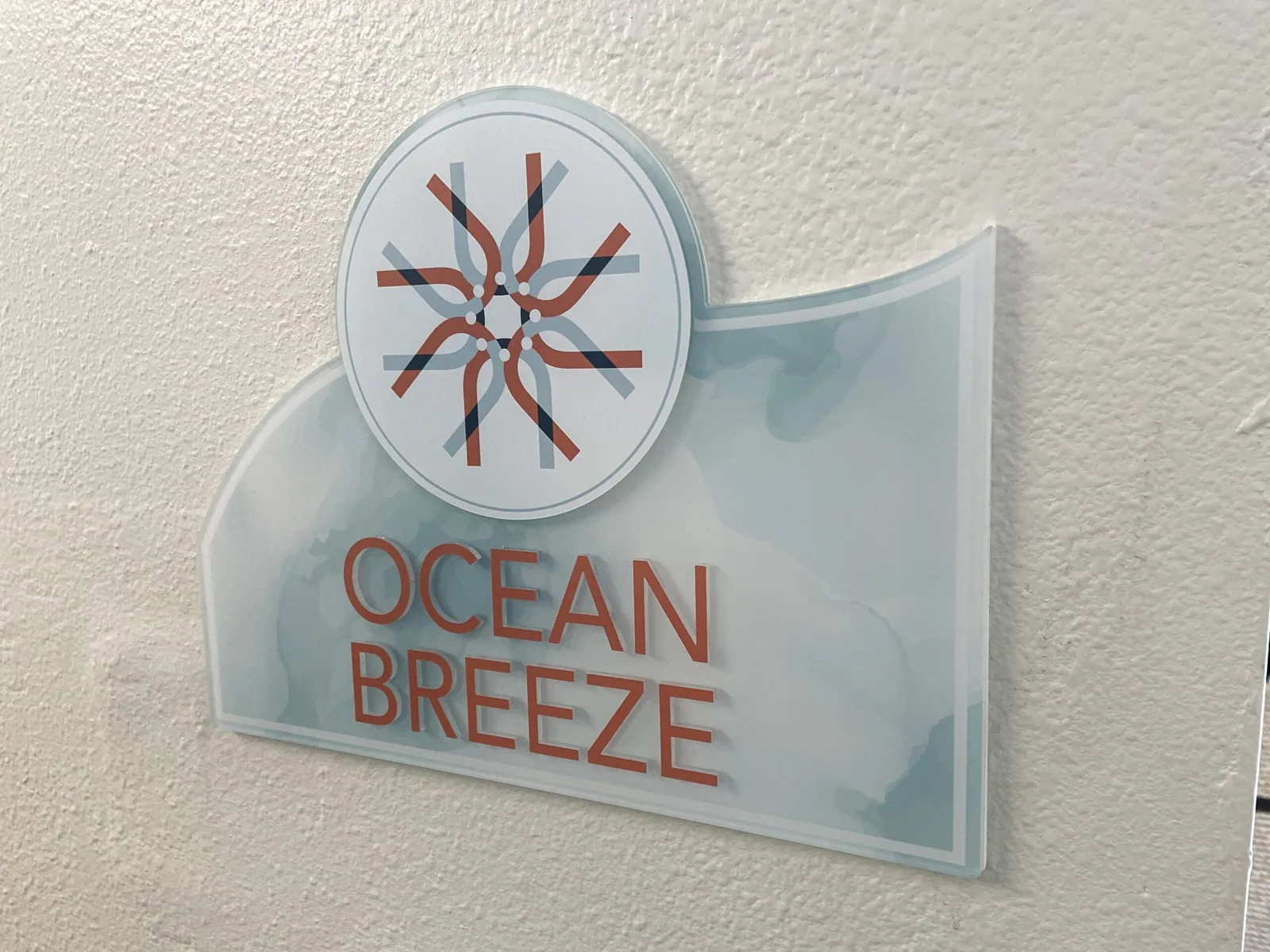 Unisen Senior Living — Ocean Breeze wall sign with logo emblem on a shaped acrylic panel, Unisen Senior Living project