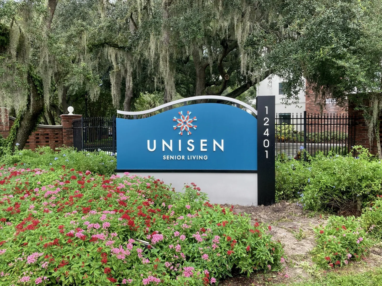 Blue Unisen Senior Living monument sign with a 12401 address post in a landscaped flower bed, Unisen Senior Living project