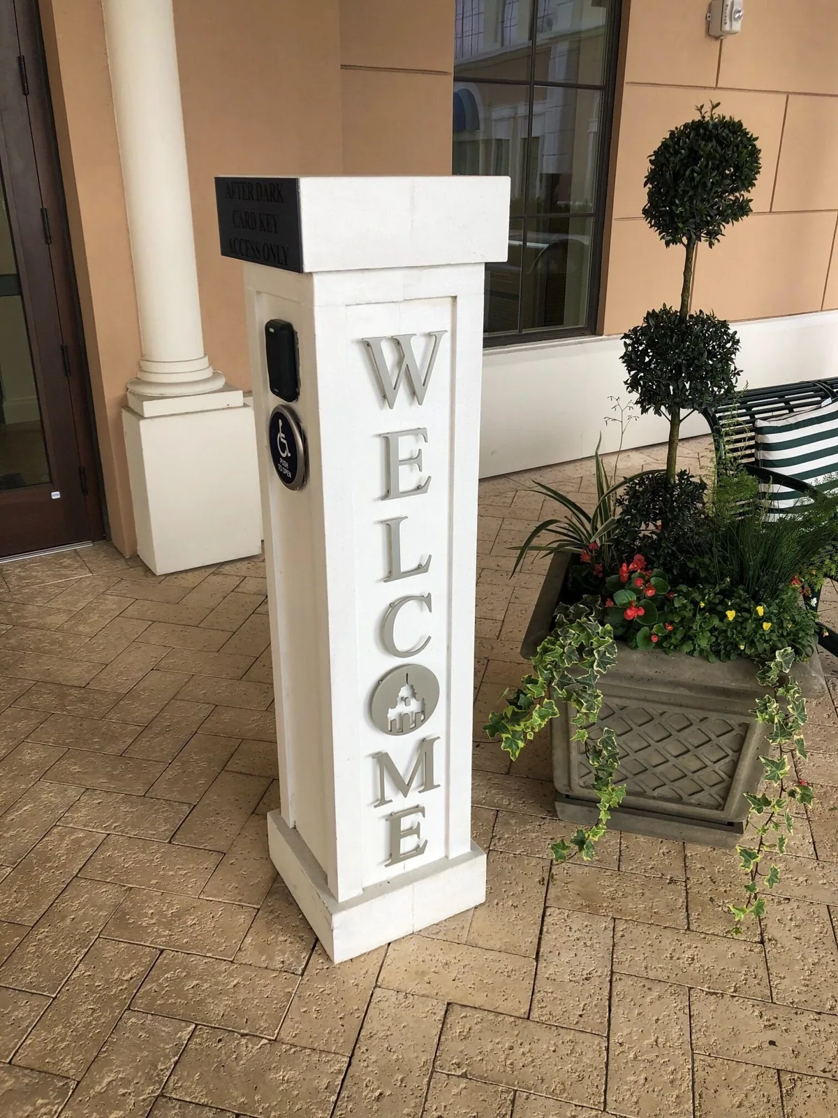 Windsor at Celebration — White Welcome post sign beside a planter at a building entrance, Windsor at Celebration project