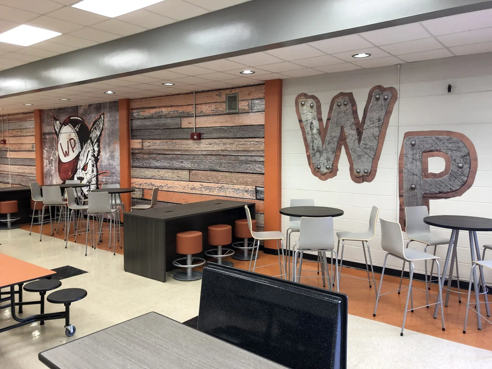 School cafeteria with a wildcat mascot mural, wood-look wall graphics and large WP letters, Winter Park High School project