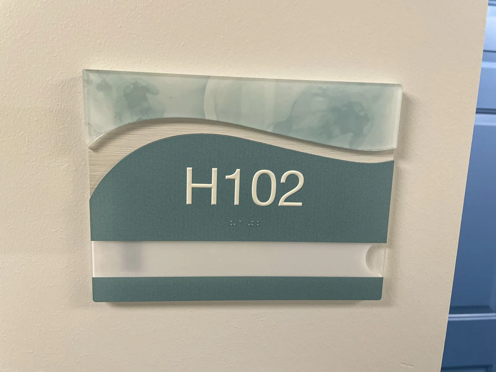 H102 room identification sign with raised numbers and Braille, Unisen Senior Living project