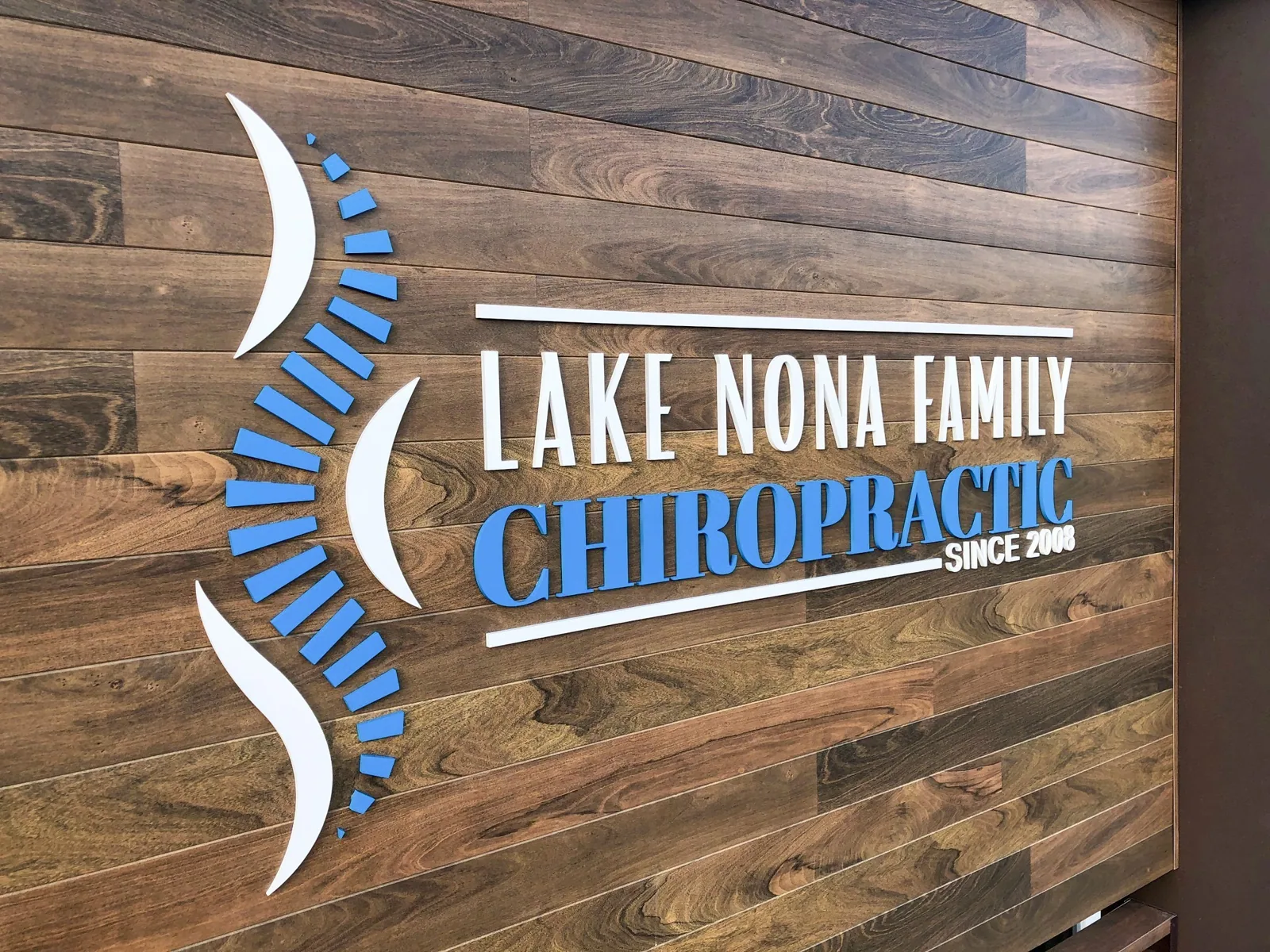 Lake Nona Family Chiropractic dimensional logo on a wood plank wall
