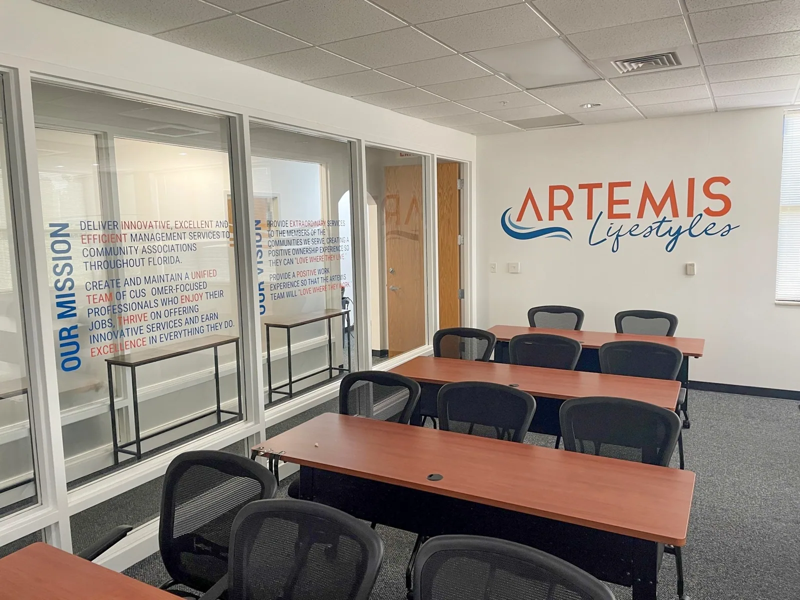 Office with Artemis Lifestyles logo wall graphic and Our Mission lettering on glass