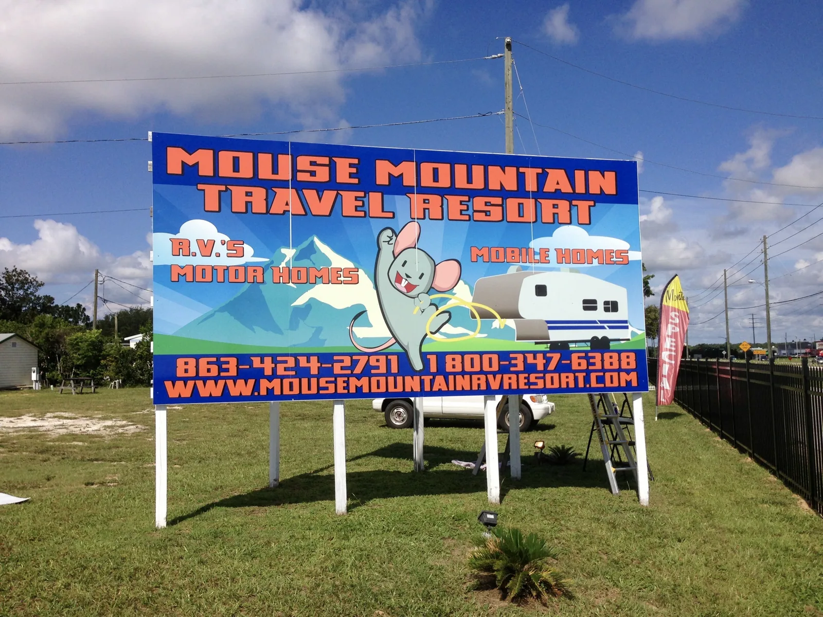 Large printed Mouse Mountain Travel Resort sign on posts along a road