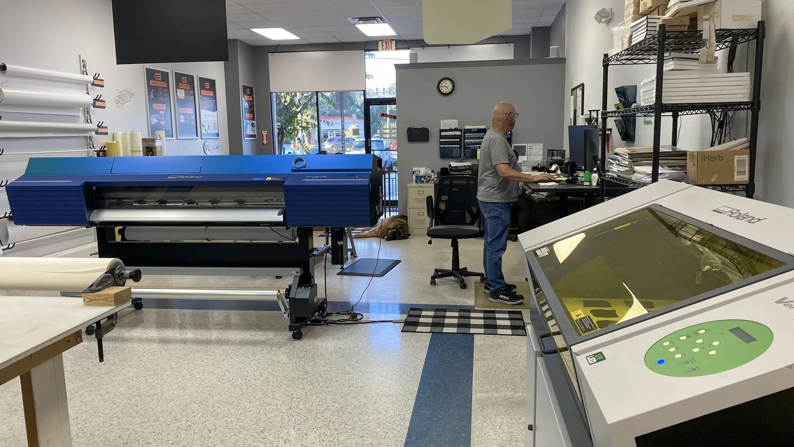 Wide-format roll printer and a flatbed printer on a print shop floor