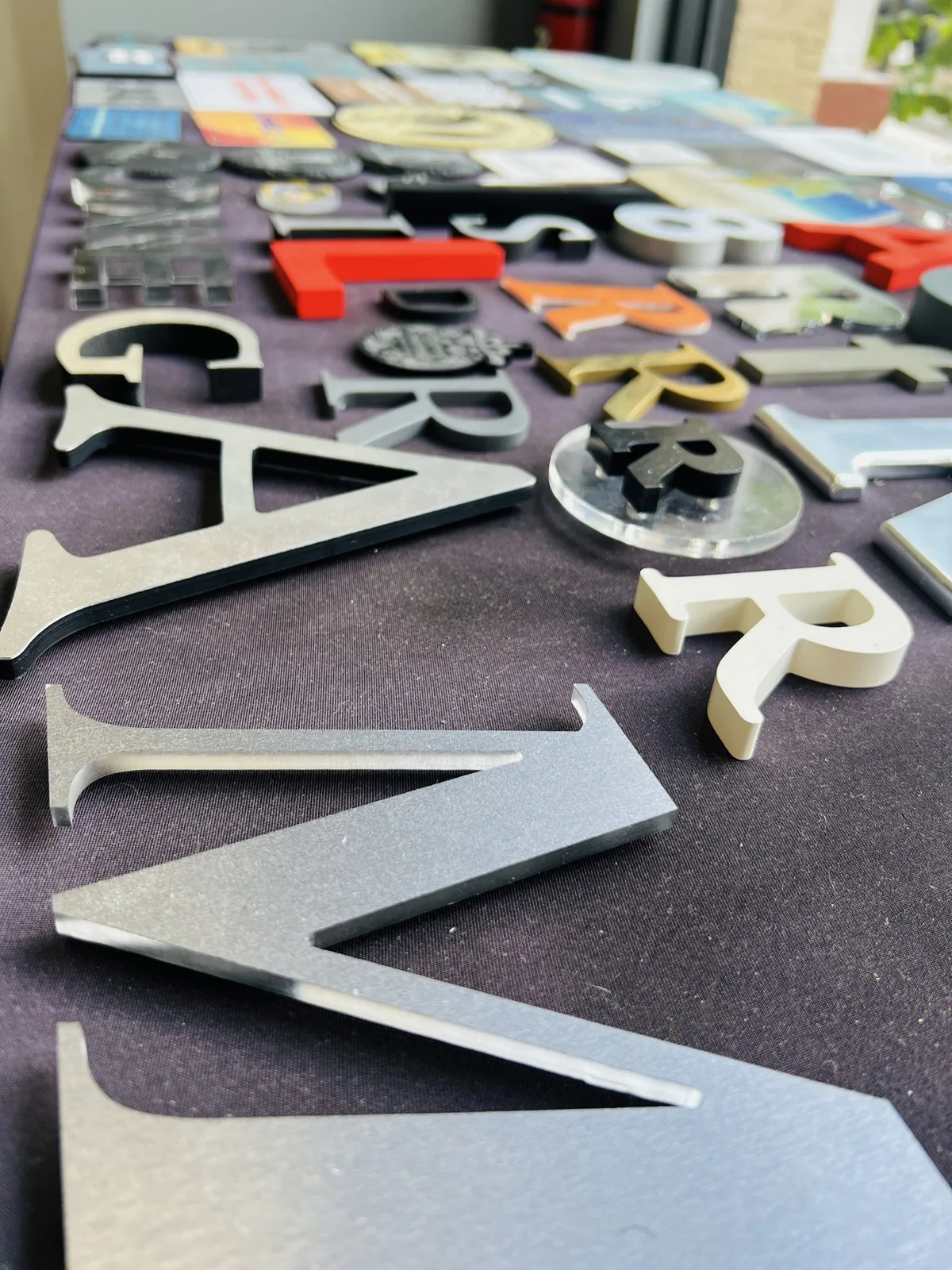 Cut dimensional letters in assorted materials and colors laid out on a table