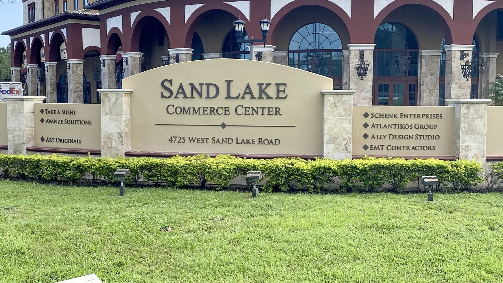 Sand Lake Commerce Center monument sign with tenant panels in front of an arched building