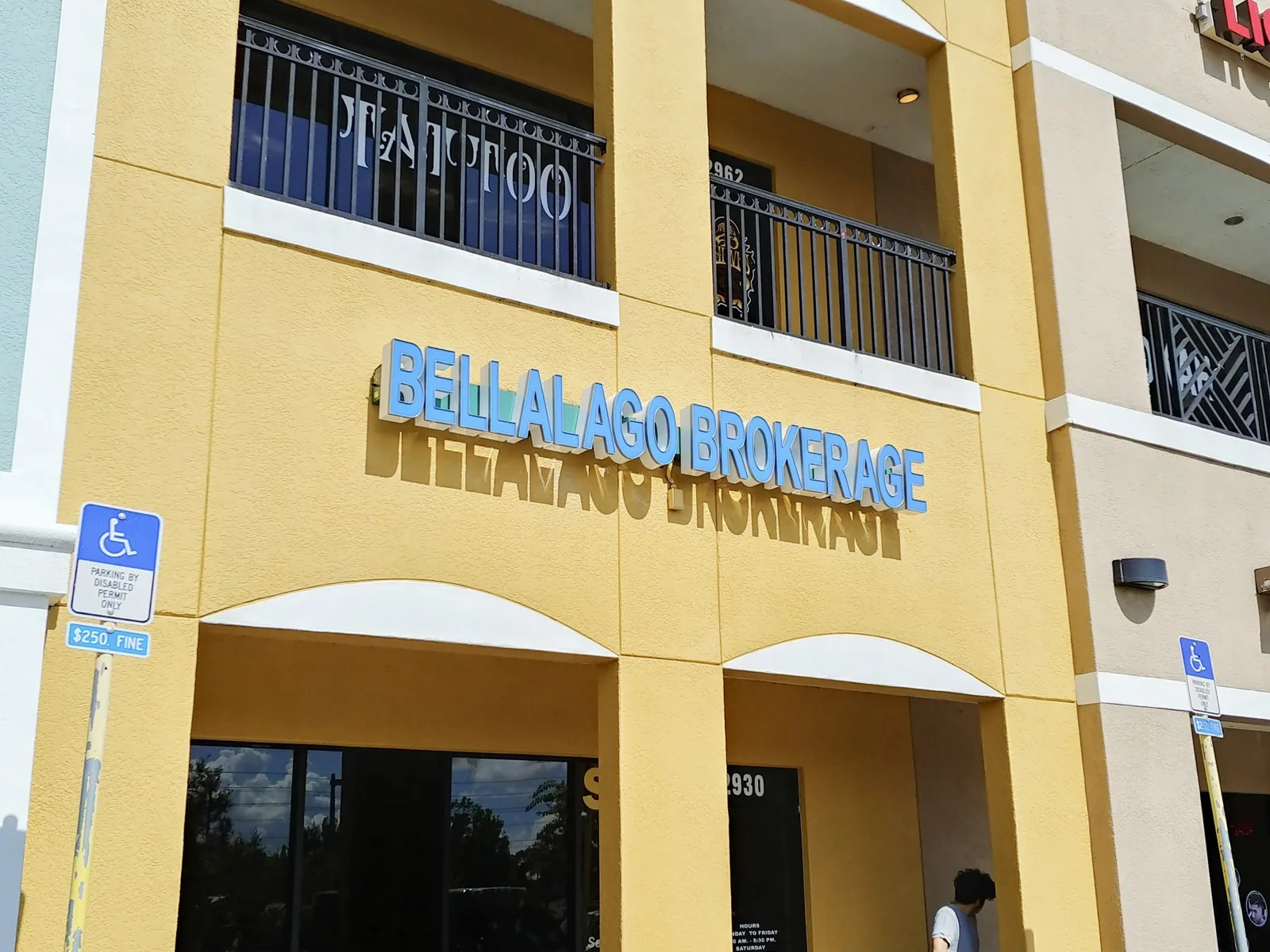 Blue BellaLago Brokerage dimensional letters on a yellow building facade